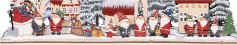 Wichtelfiguren in roter Kleidung mit Geschenken vor Weihnachtsbaum und winterlichem Hintergrund – Teil des LED-Dioramas „Wichtelhausen“.