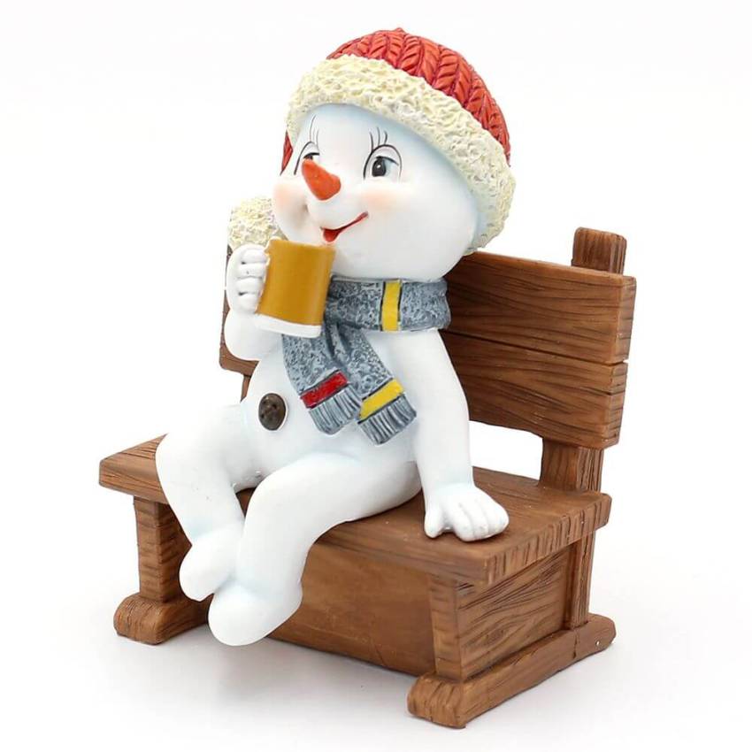 Ein Polyresin-Schneekind "Feierabend" mit Mütze und Schal, sitzend auf einer Bank, genießt vermutlich ein Bierchen.